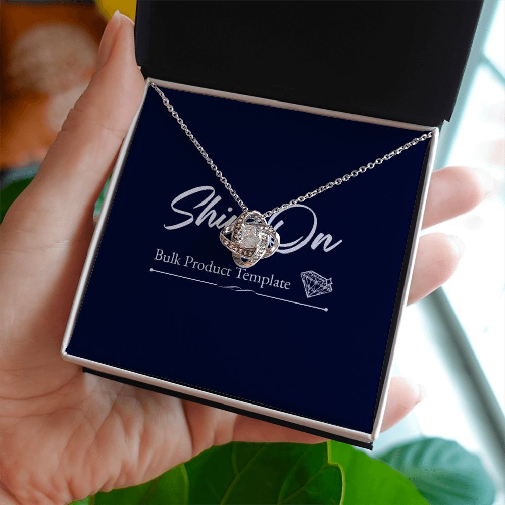 A hand holds a luxury box and knot necklace on a message card